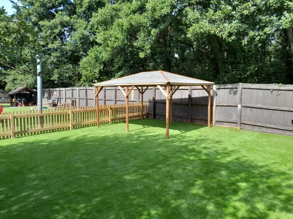 A school play area on artificial grass with a wooden gazebo