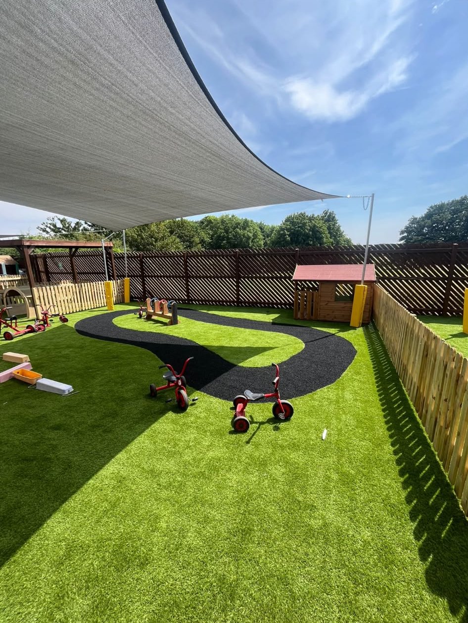 A nursery play area on artificial grass with a trike track